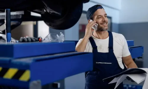happy-mechanic-talking-phone-while-working-auto-repair-shop_637285-12719
